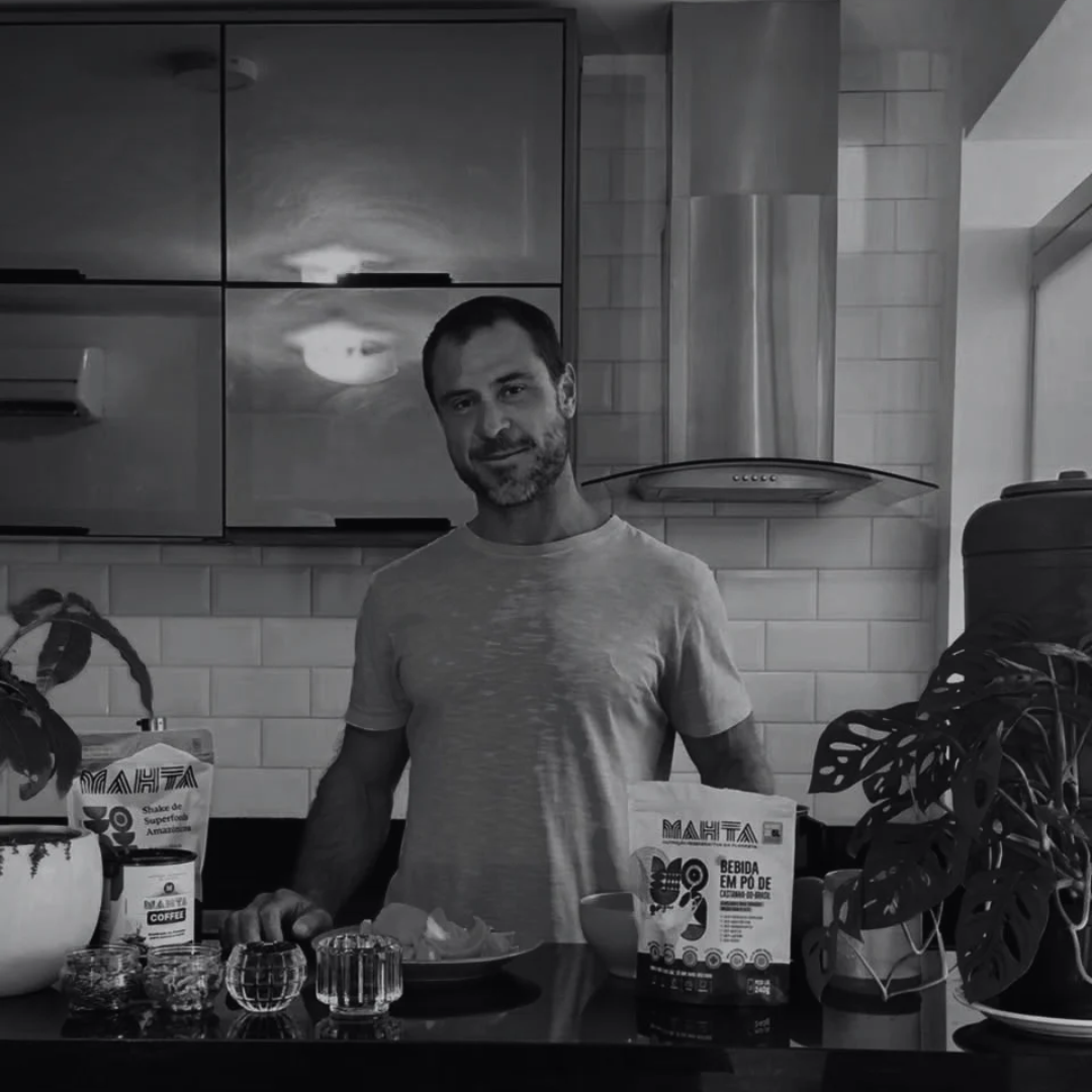 Augusto Penteado preparando alimentos e bebidas funcionais na cozinha, em preto e branco