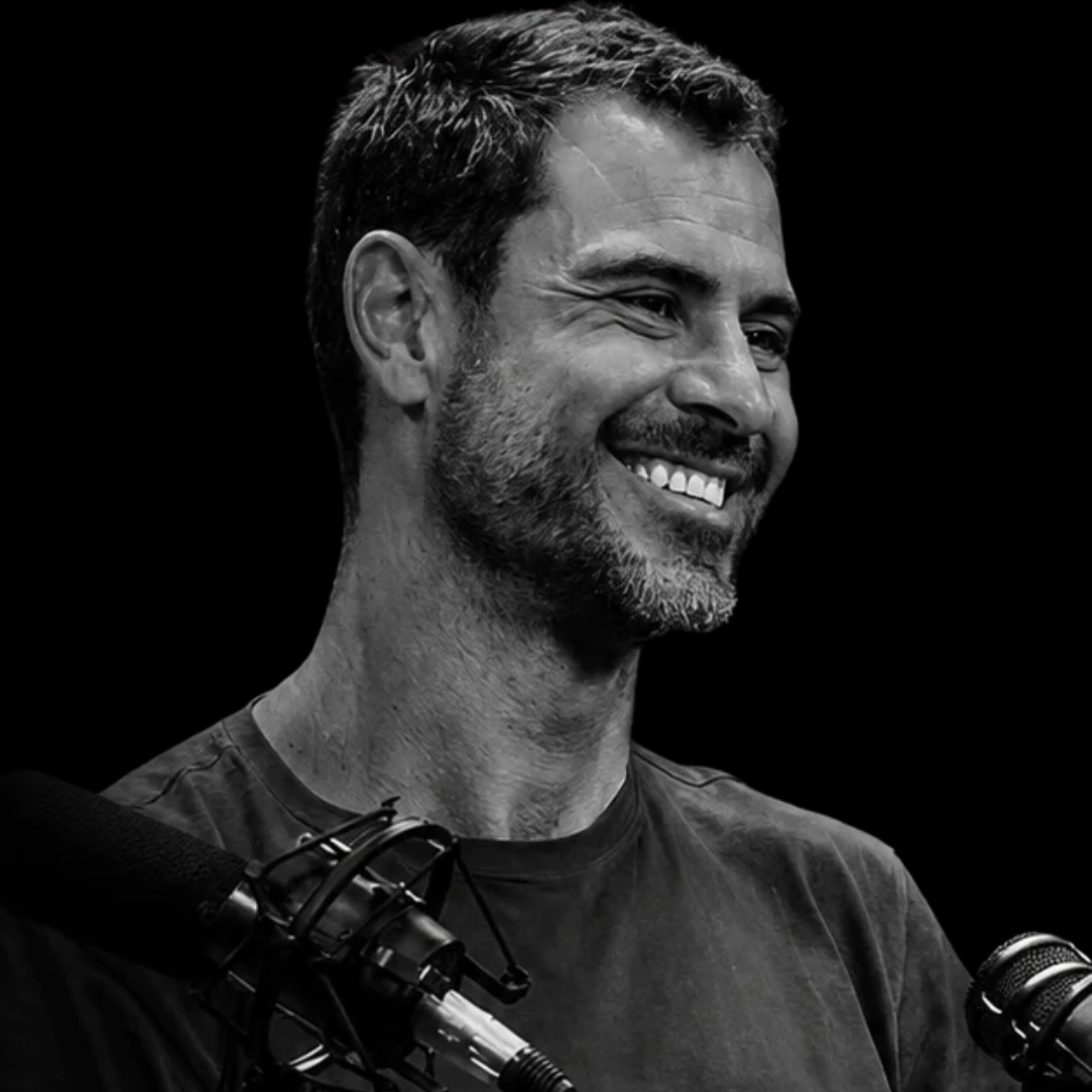 Retrato de Augusto Penteado sorrindo diante de um microfone, em preto e branco